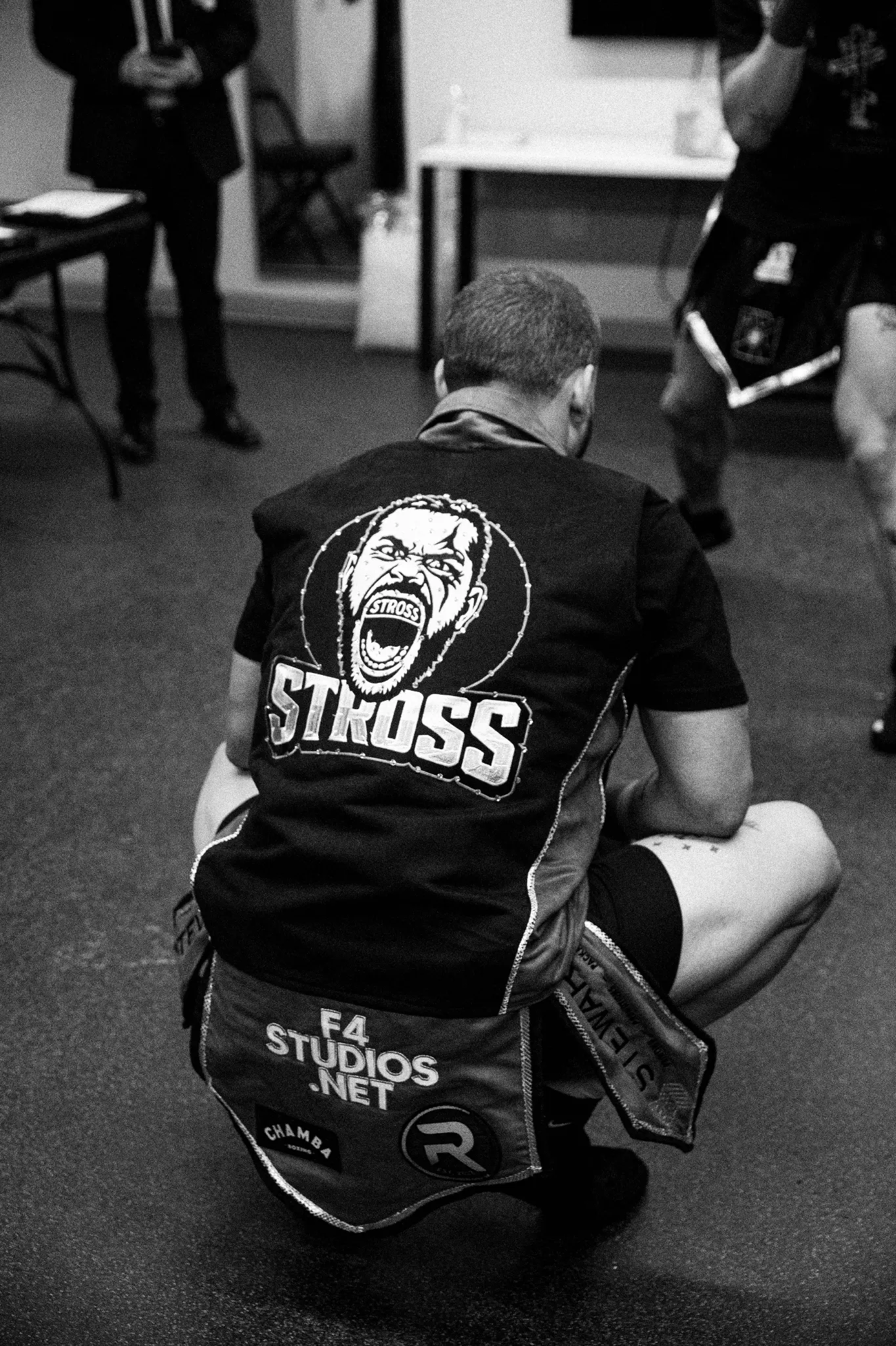 Black-and-white photograph of a fighter sitting backstage before a bout.