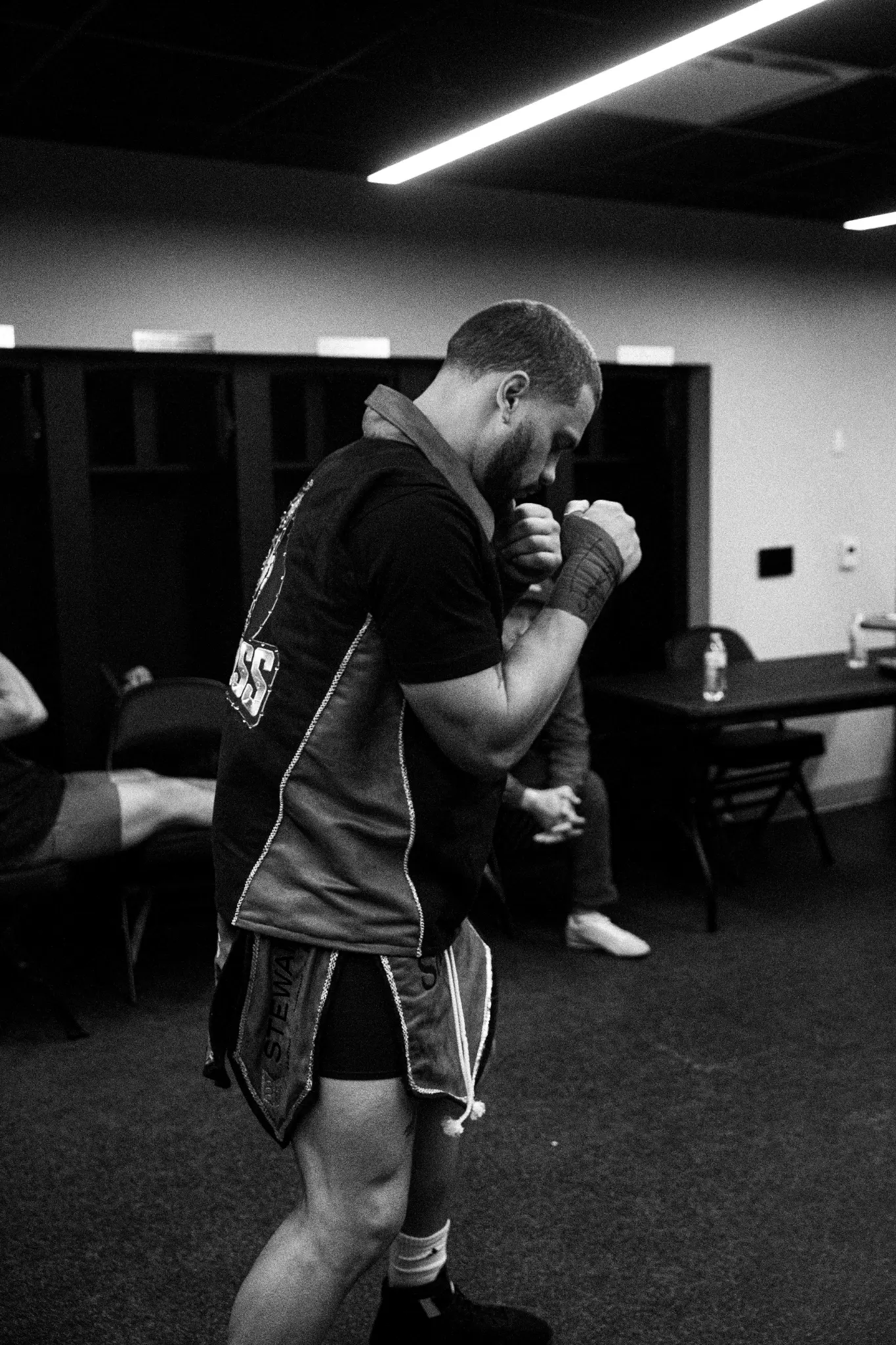 Black-and-white candid of a boxer preparing in a locker room.
