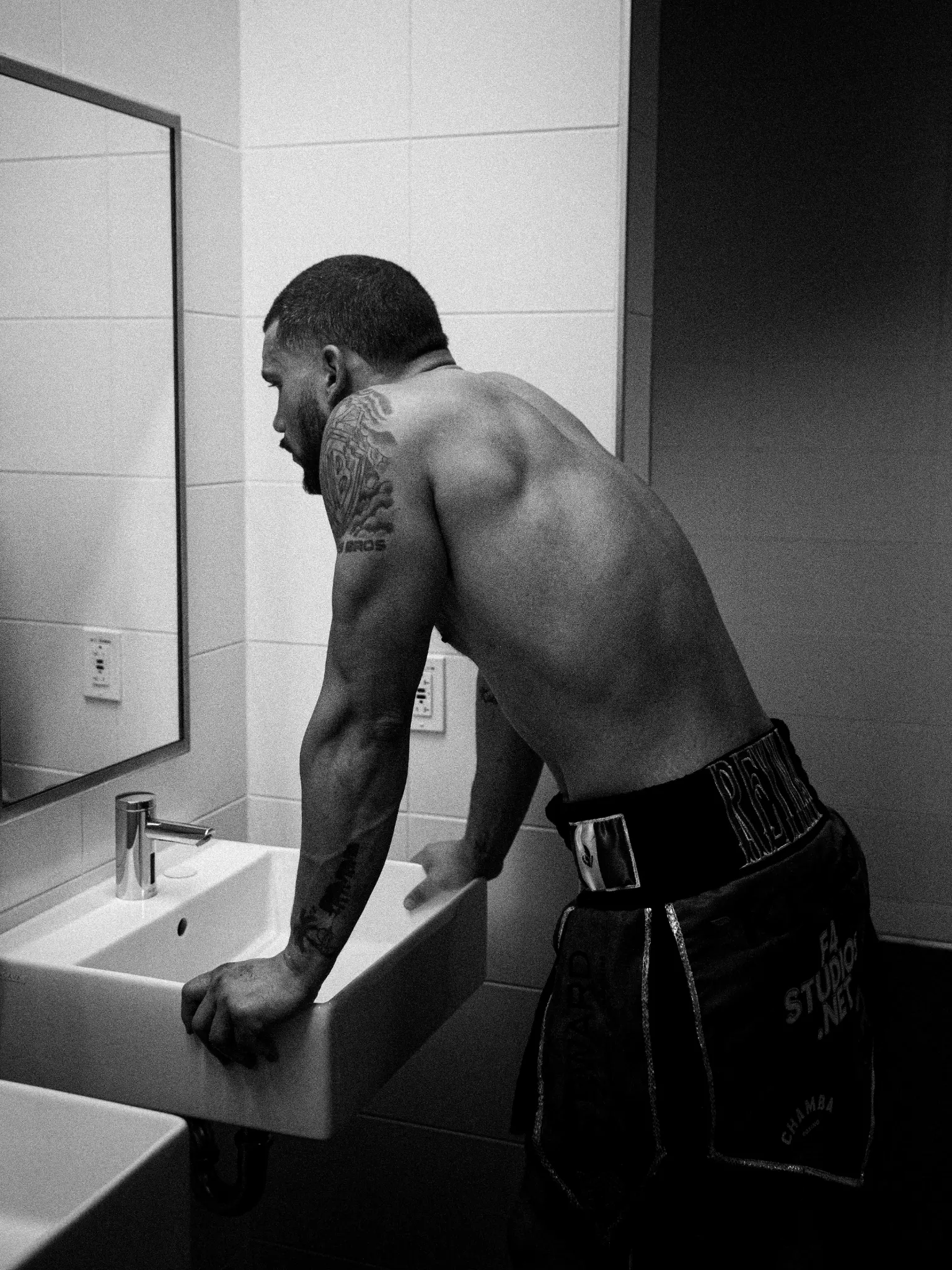 Black-and-white backstage portrait of a boxer beside a mirror.