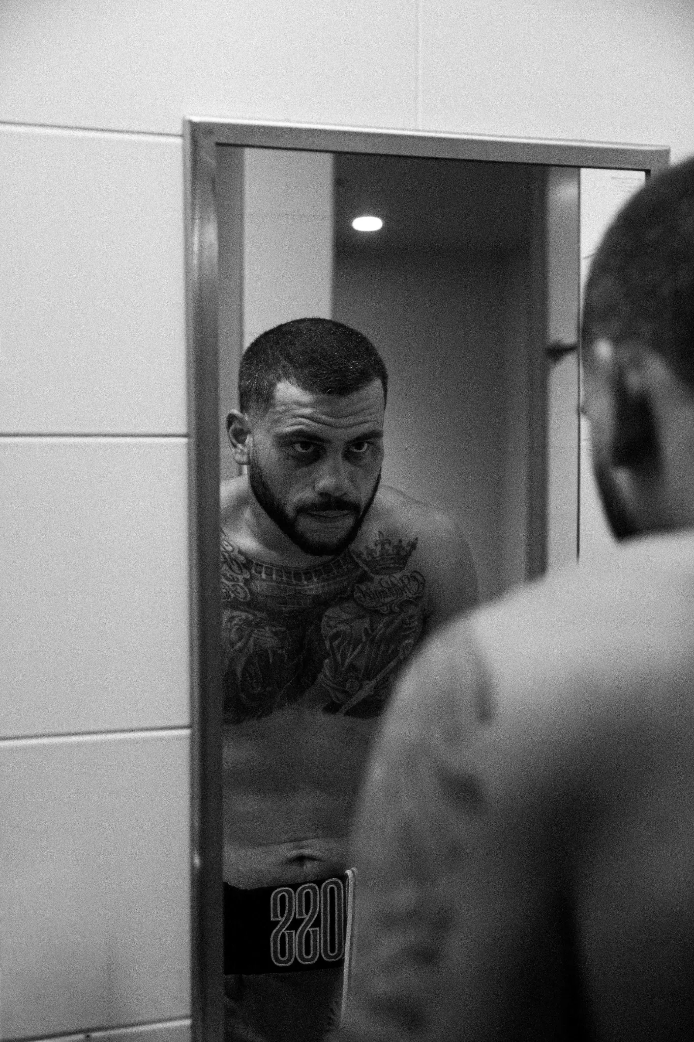 Black-and-white mirror portrait of a fighter preparing backstage.