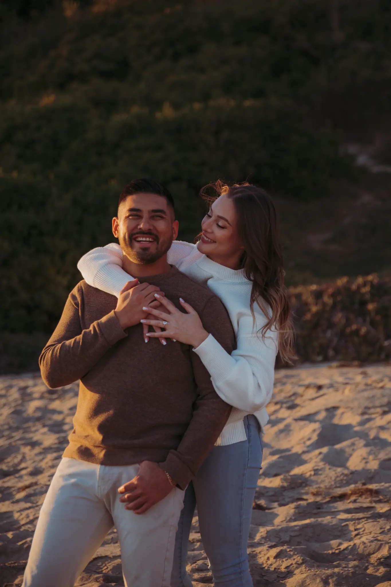 Couple standing together on a beach at golden hour.