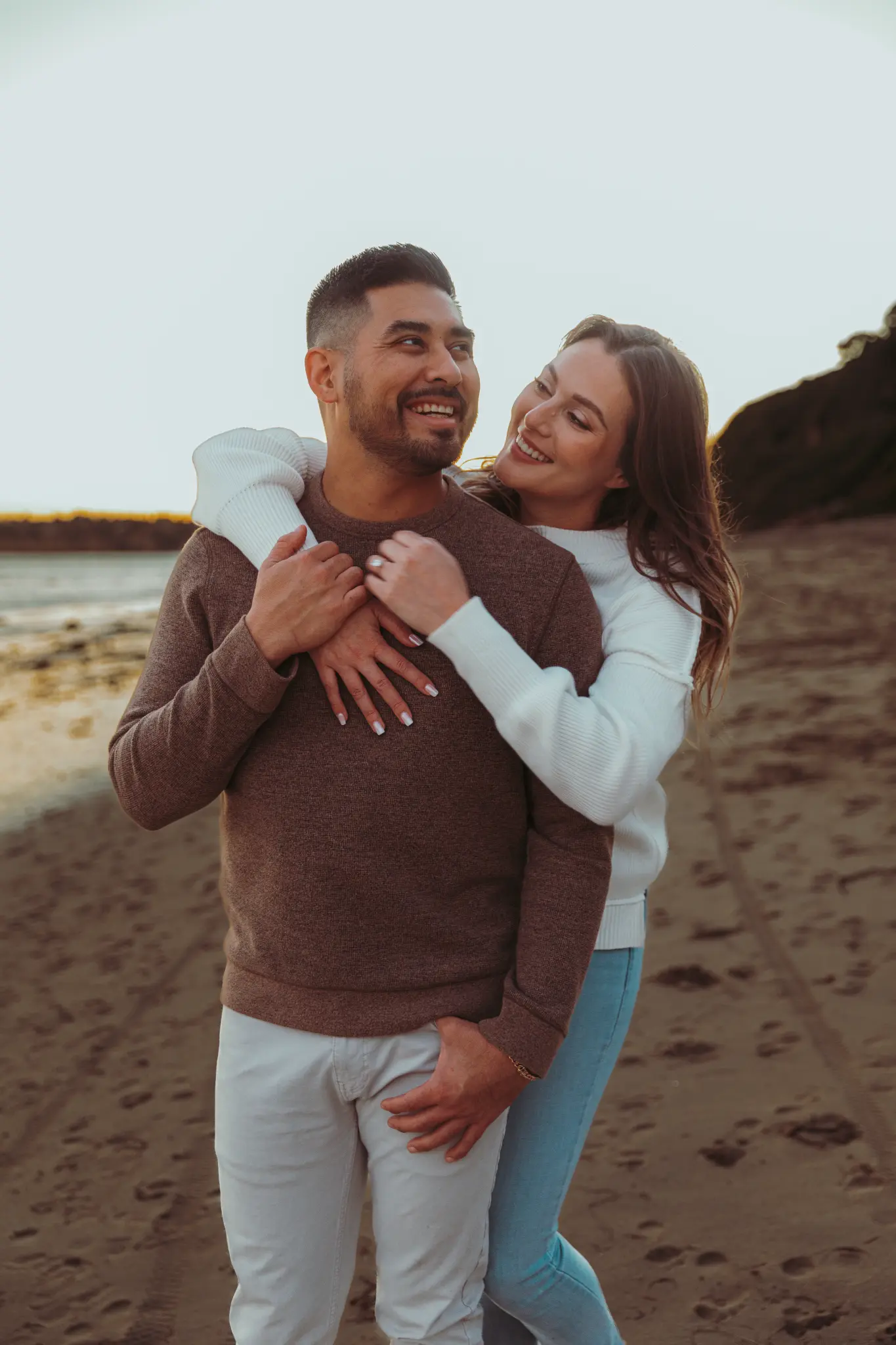 Couple embracing at the beach in warm evening light.