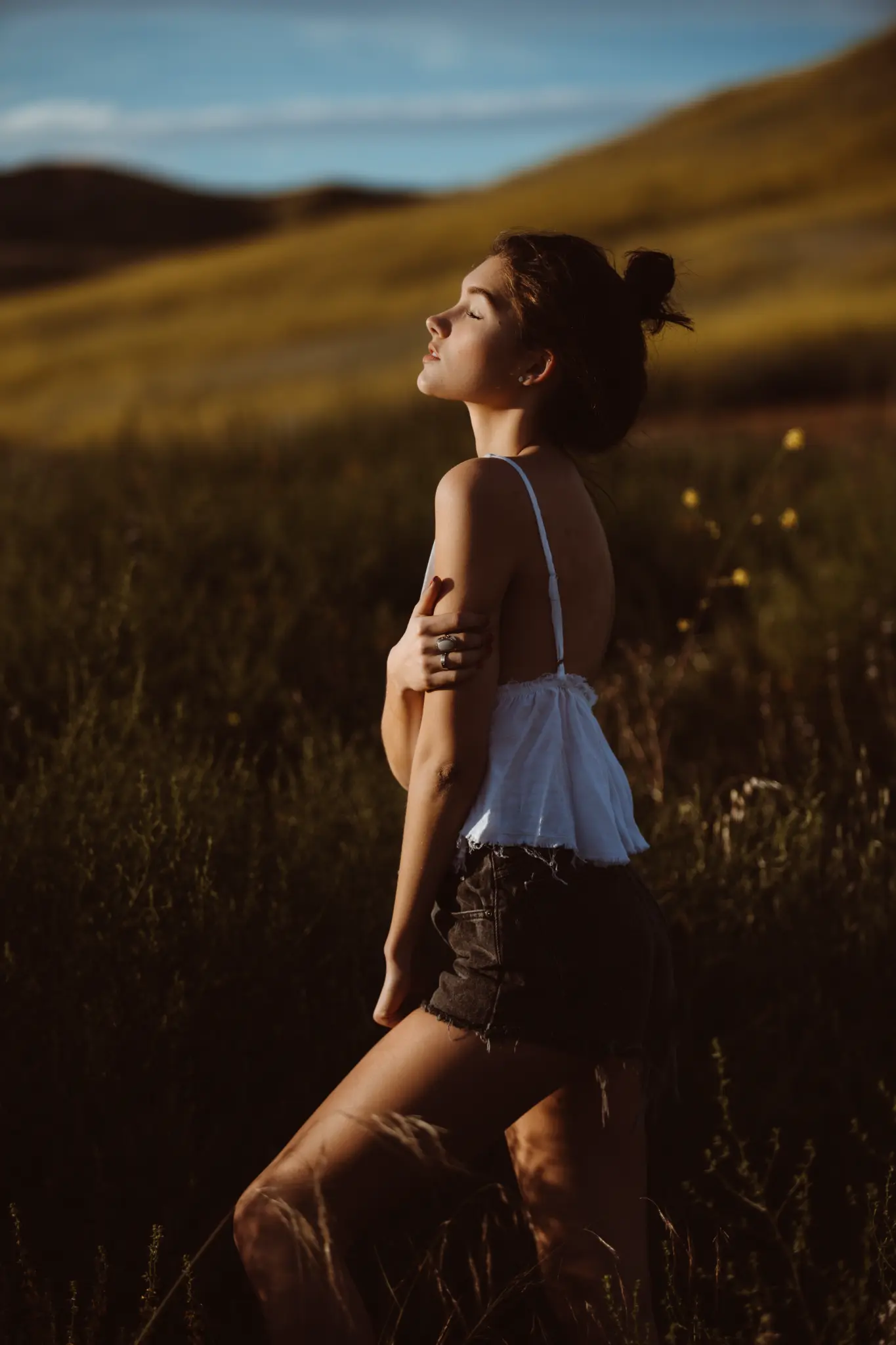 Sunset portrait of a woman standing in open hills.