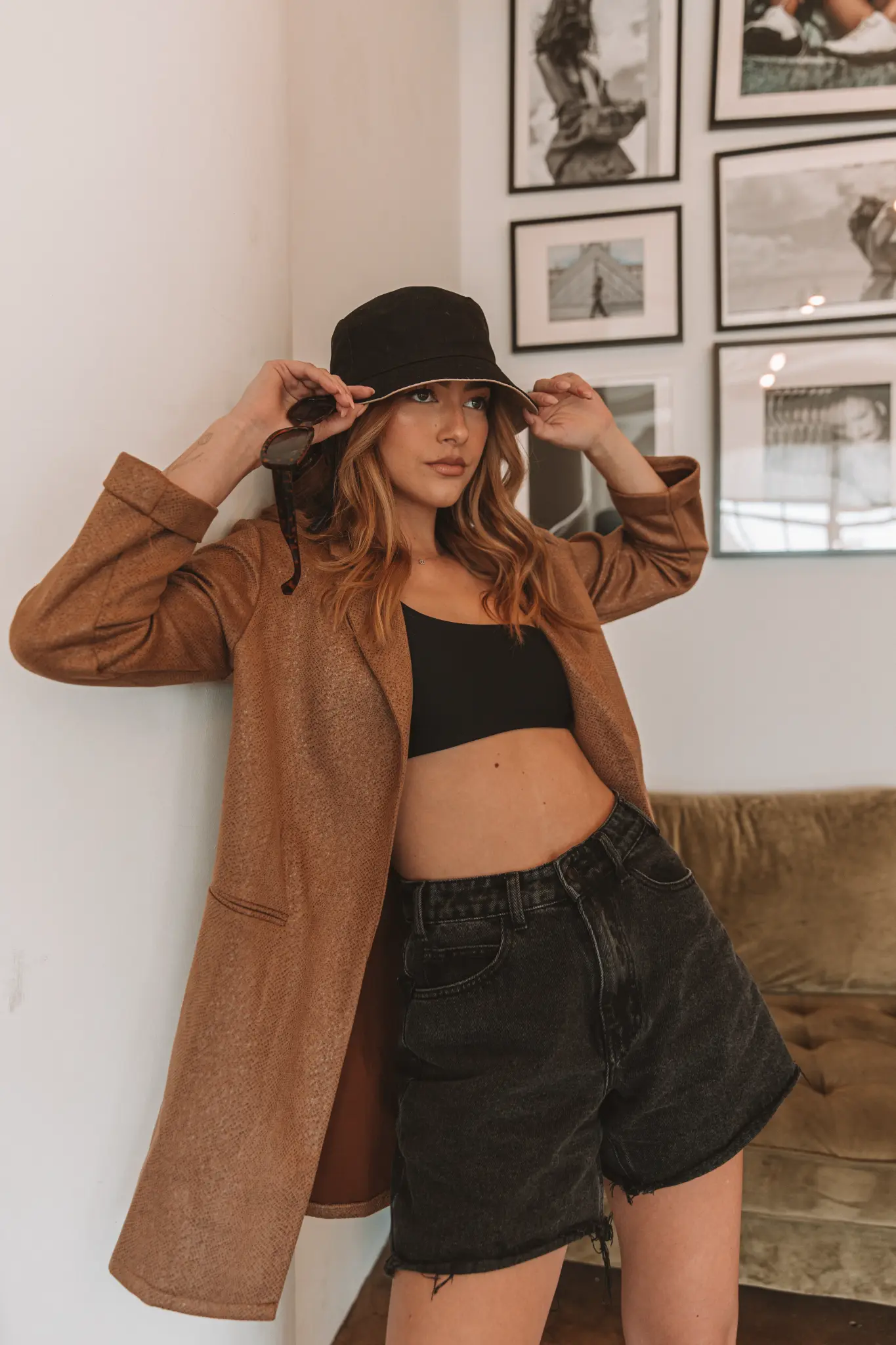 Full-length fashion portrait of a woman in a black hat and brown coat.